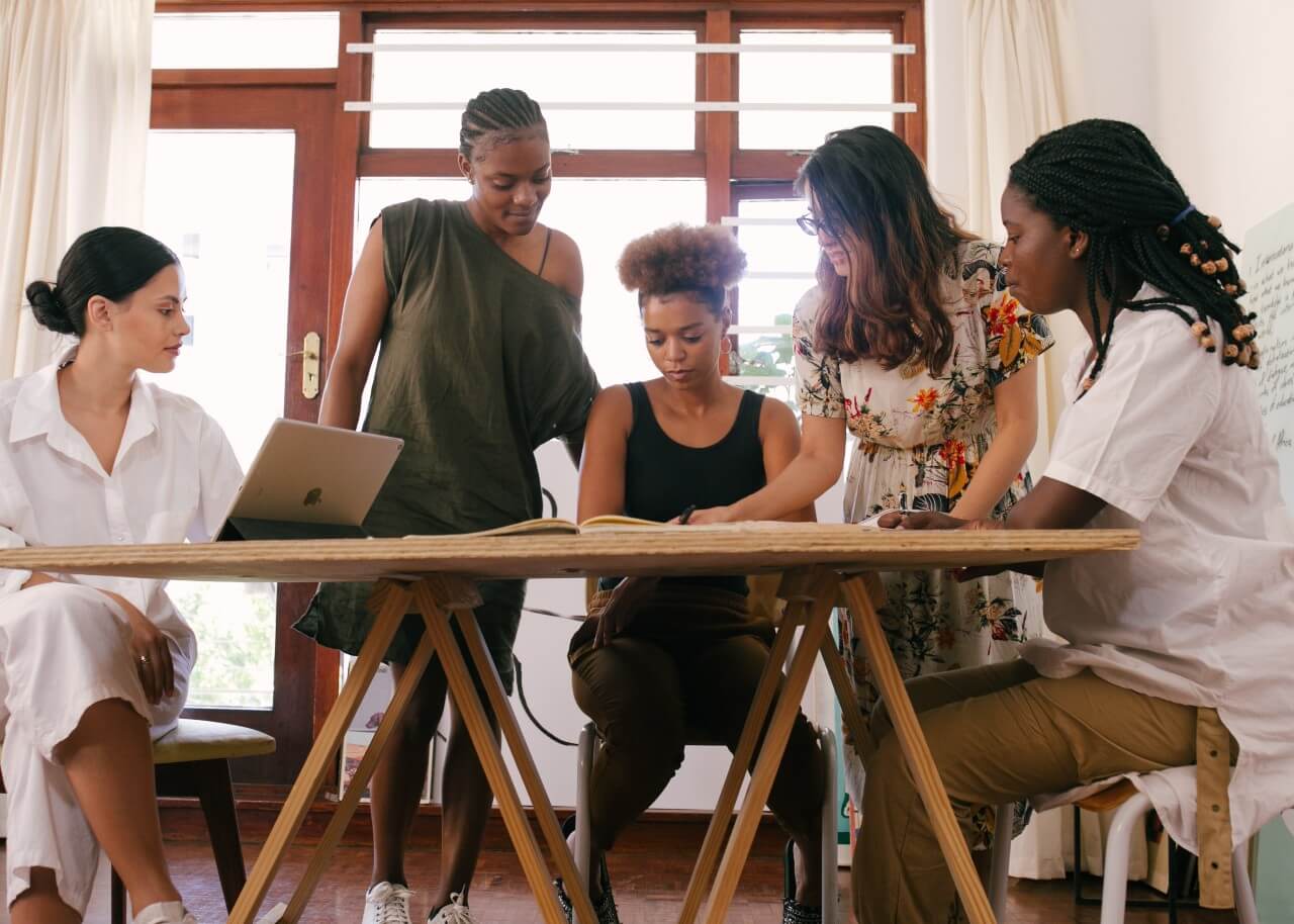 A group of colleagues sit around a desk working on a piece of work together