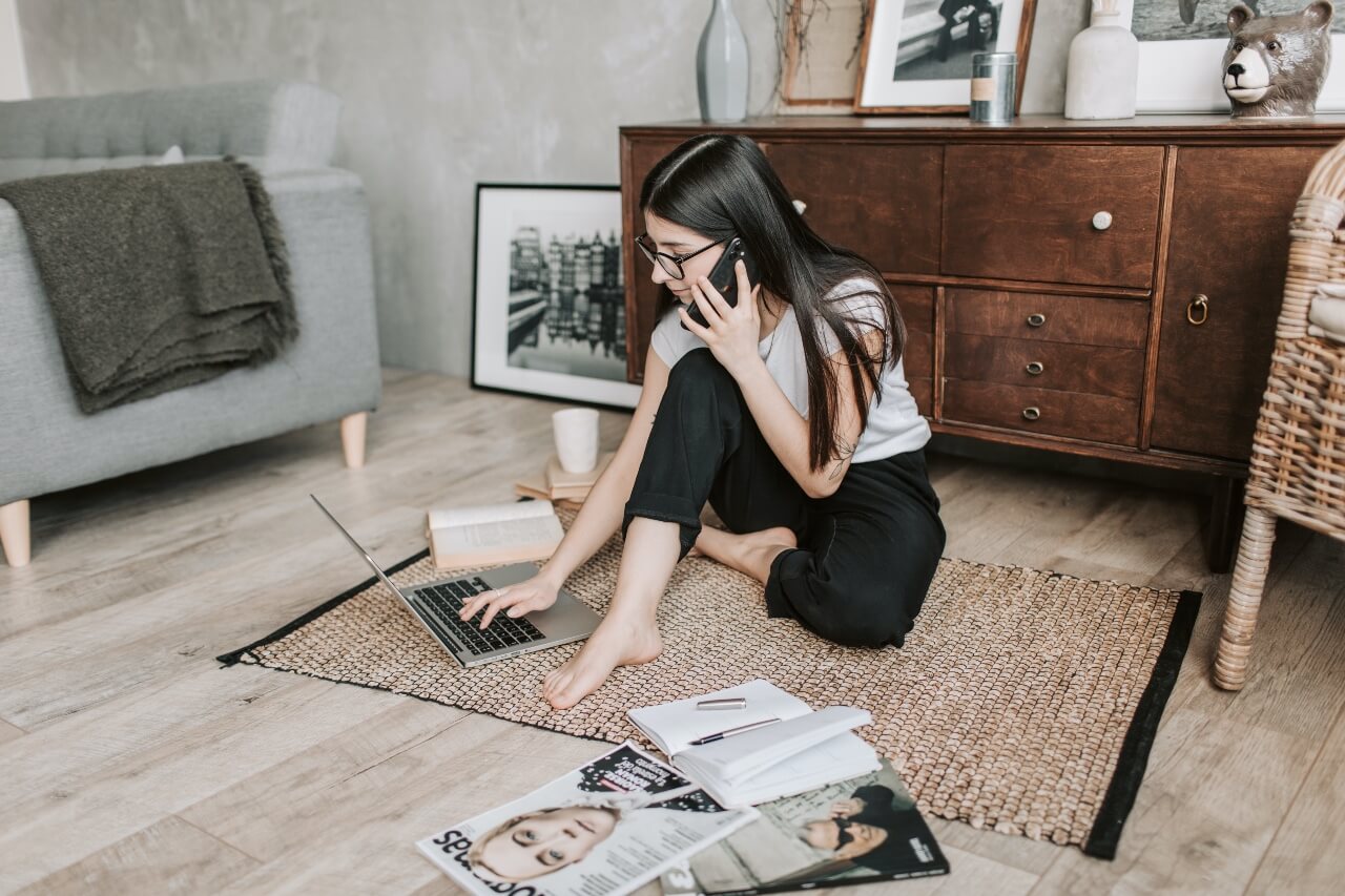 woman using laptop while having a conversation on her phone