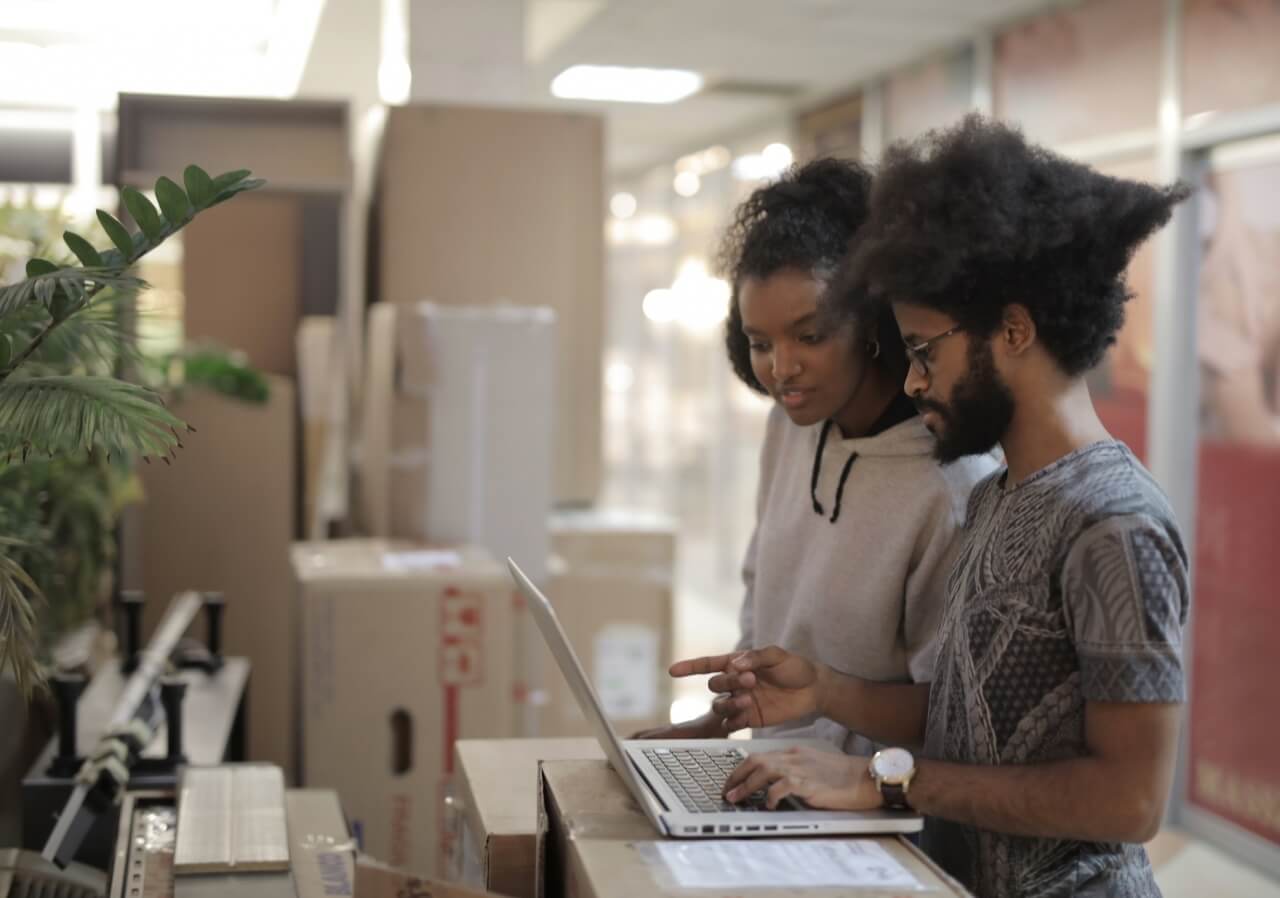 Two colleagues discuss business matters over a laptop