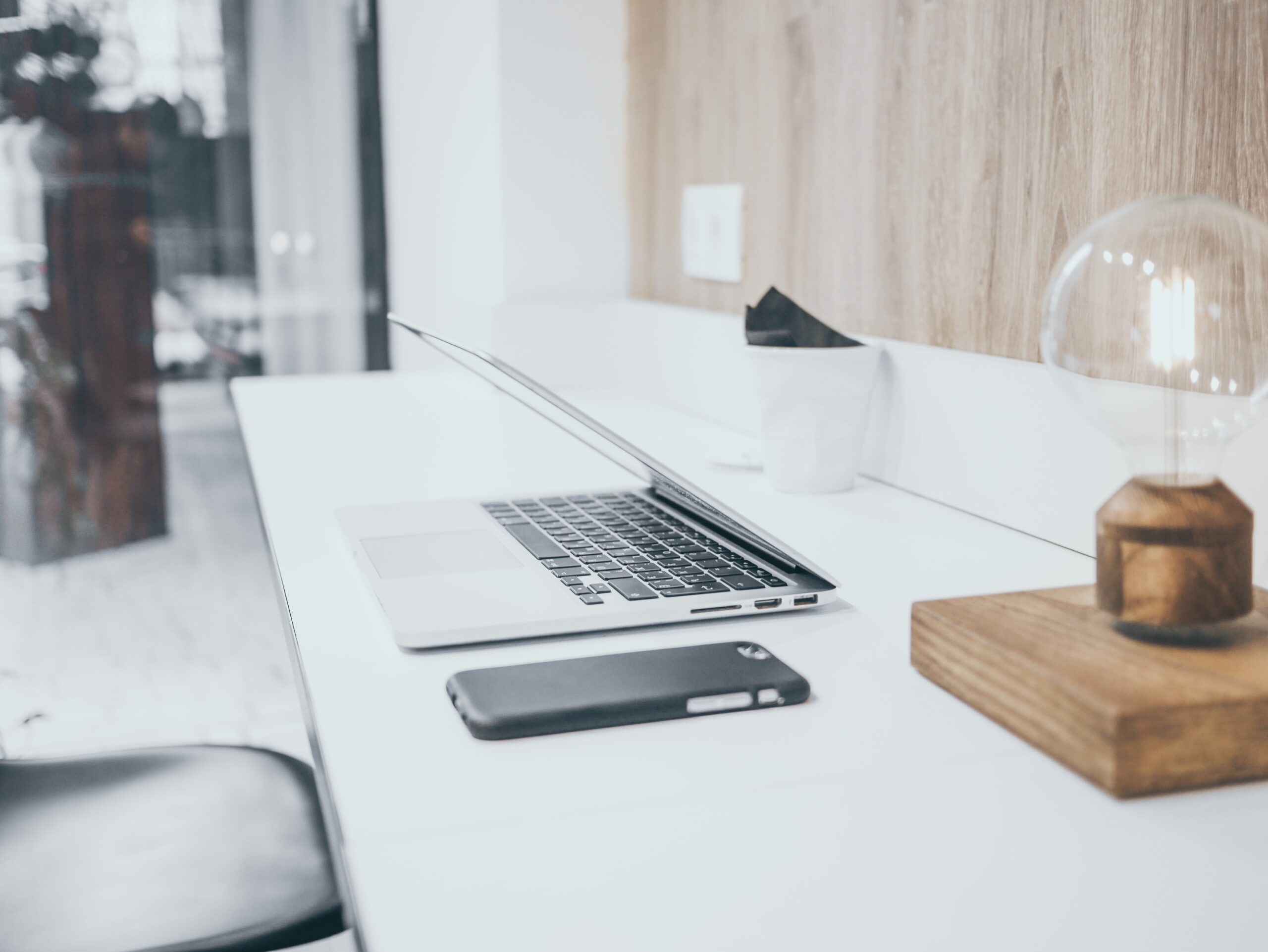 laptop, mobile phone, cup and lightbulb-shaped lamp on desk