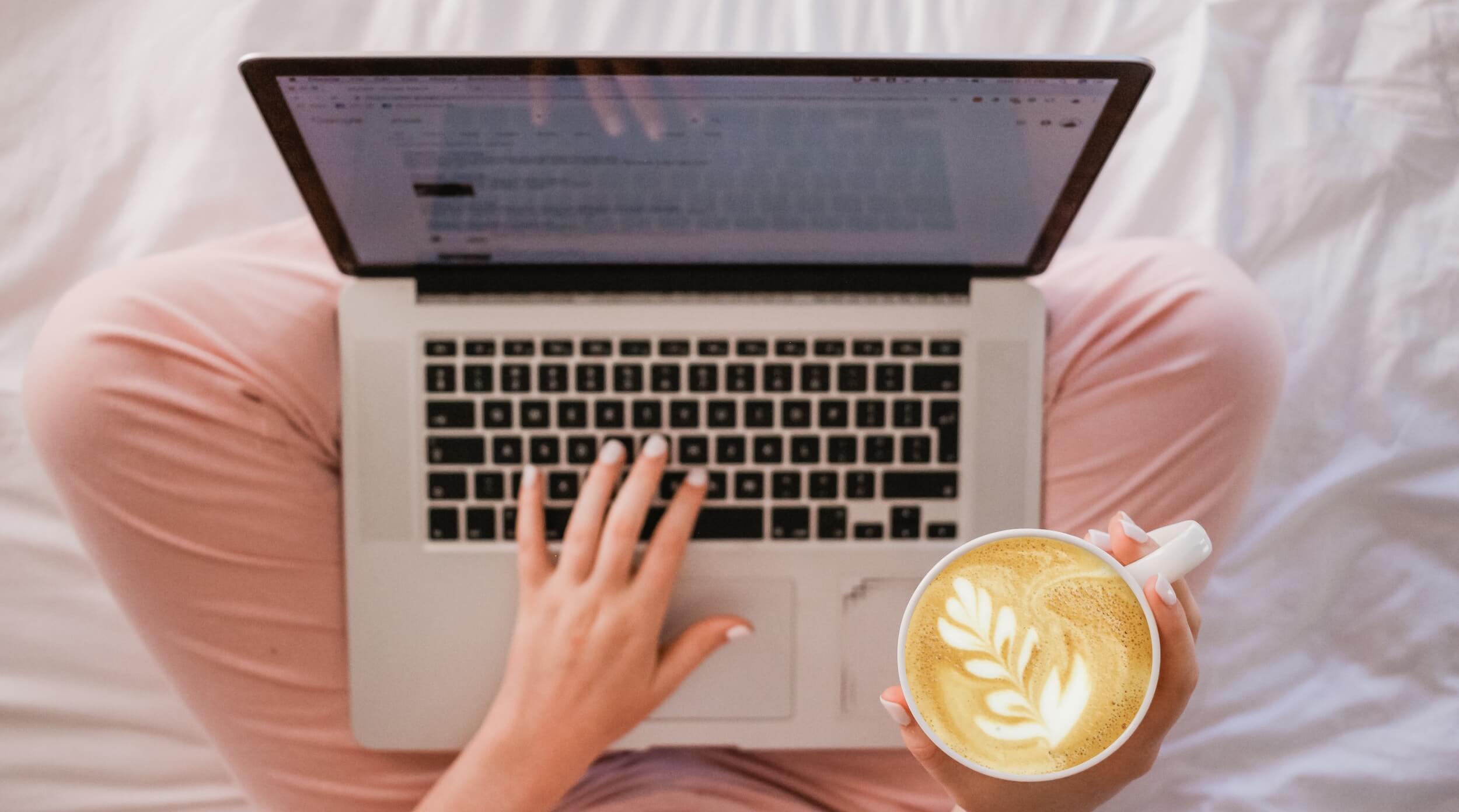 Woman on laptop holding coffee